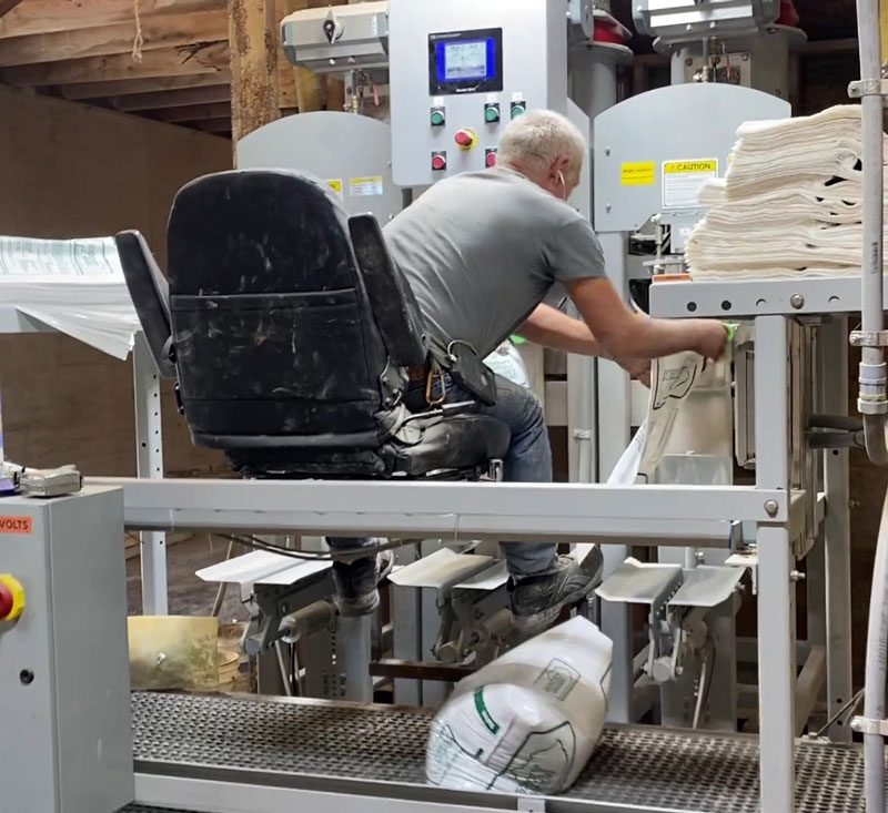 bags of fertilizer on discharge conveyor under operators chair with valve bag fillers