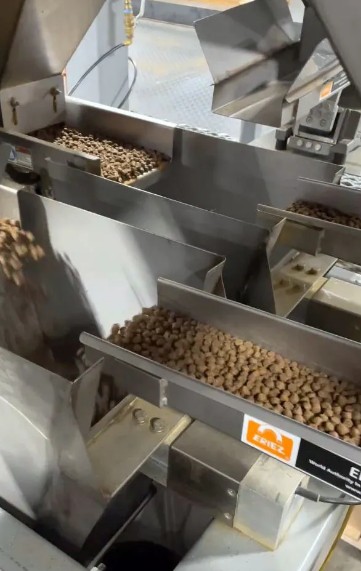 Vibratory feeders above net weigh bag fillers