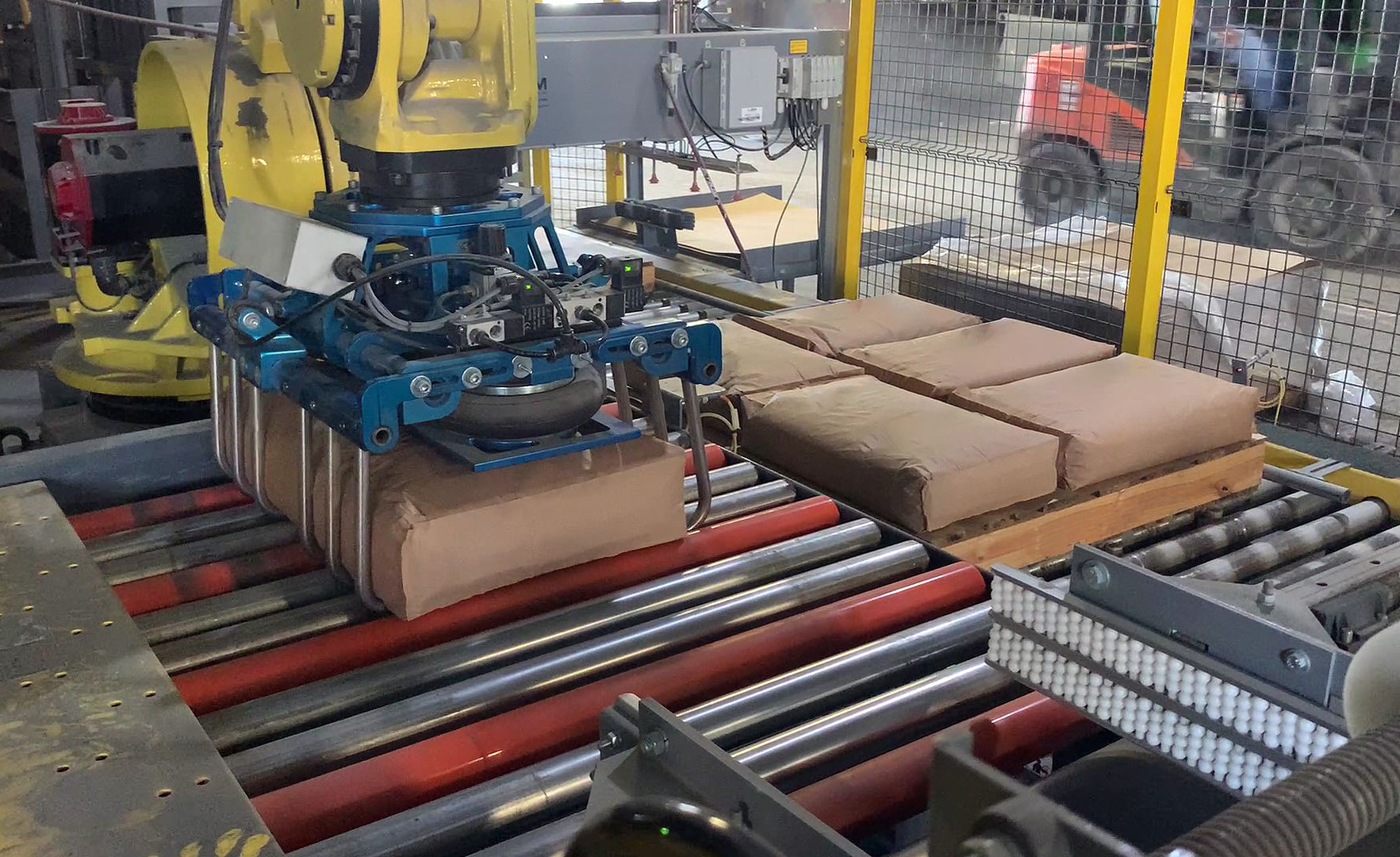 Fanuc robot picking up 100 lb. bag of minerals using a bag gripper tool
