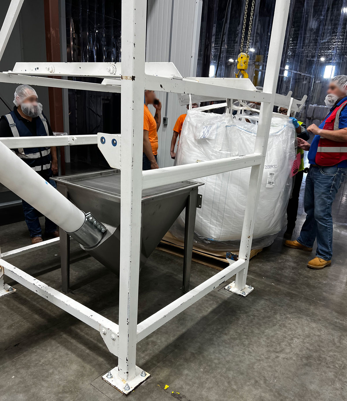 Loading a bulk bag containing granulated sugar into unloader over screw conveyor system