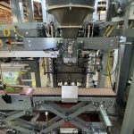 bird seed bag moving through bag top reformer before band heat sealer